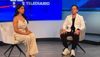 Se observa a una mujer y un hombre sentados con un fondo azul.