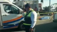Policía hablando por teléfono junto al cuerpo de una persona muerta.