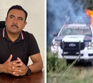 Hombre de playera negra hablando junto a una fotografía de una patrulla en llamas.