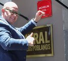 Hombre colocando una placa roja afuera de un restaurante en Puebla.