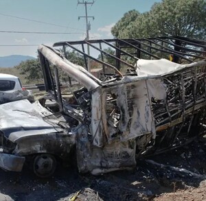 Camioneta de carga quemada en medos de una carretera de Jalisco con un auto pasando al lado durante captura de El Mencho