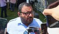 Hombre de barba y lentes siendo entrevistado por varias personas.