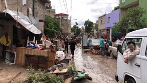 Colonia La Martinica tras inundación con muebles tirados en medio de la calle, autos varas y personas caminando alrededor