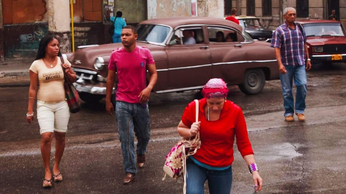 Una calle de Cuba con personas y un auto