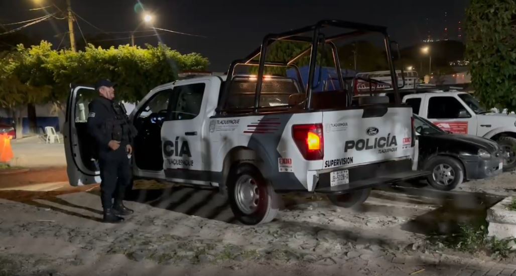 Patrulla de la Policía de Tlaquepaque con un oficial para a un lado a un costado de la calle