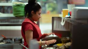 Una mujer joven con un delantal rojo vista de perfil en una cocina