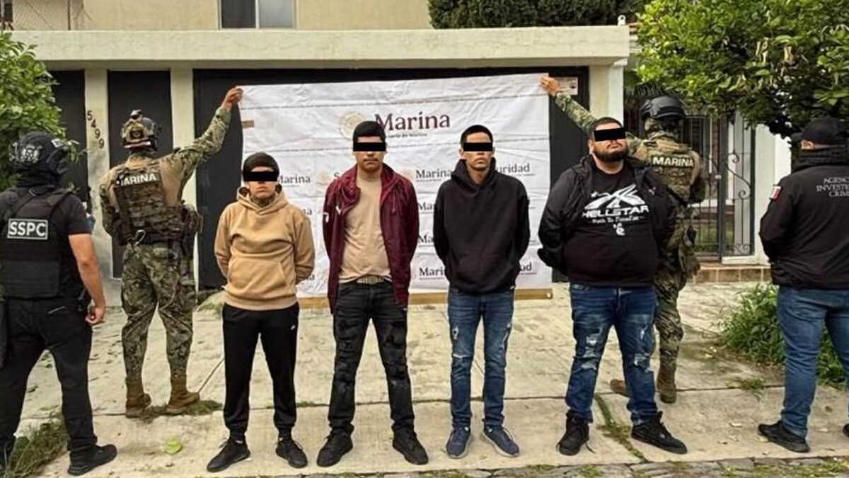 Cuatro hombres con los ojos censurados por un cuadro negro, siendo detenidos por agentes federales y militares de la Marina frente a una casa en Zapopan