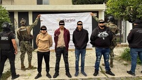 Cuatro hombres con los ojos censurados por un cuadro negro, siendo detenidos por agentes federales y militares de la Marina frente a una casa en Zapopan