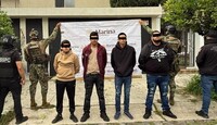 Cuatro hombres con los ojos censurados por un cuadro negro, siendo detenidos por agentes federales y militares de la Marina frente a una casa en Zapopan