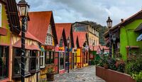 Casas con fachadas europeas y estéticas navideña con muchos colores, plantas alrededor y un cielo nublado en Tlalpujahua