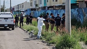Peritos del IJCF y oficiales de la Policía de Tlajomulco en un área con maleza al lado de un canal donde fue hallado un cuerpo