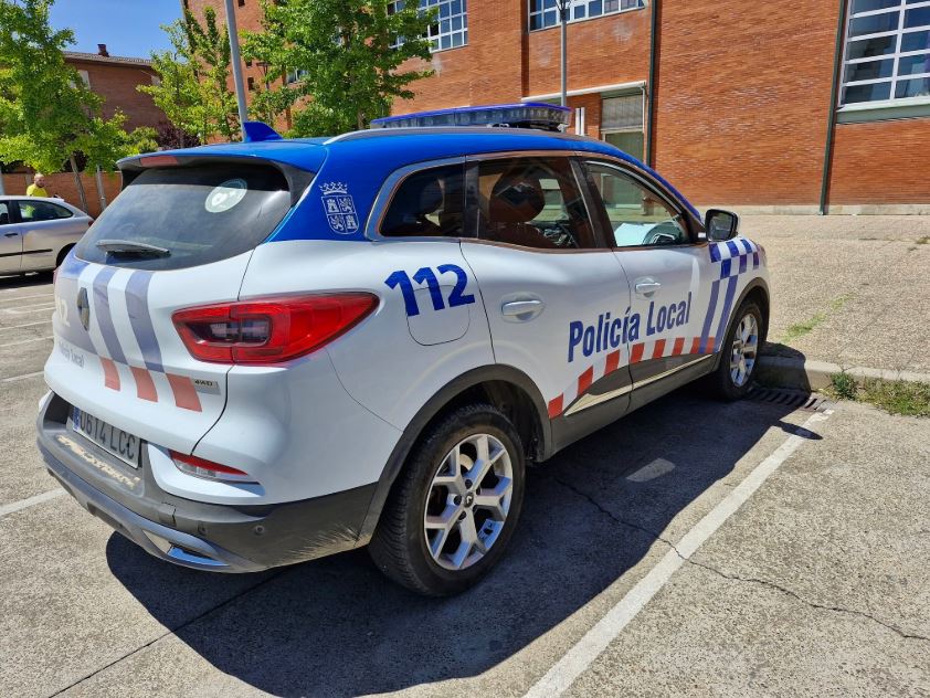 Vista del costado de una patrulla de la Policía Local Palencia estacionada al exterior de un edificio
