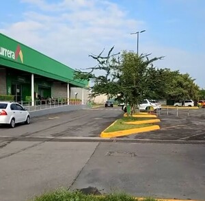 Área del estacionamiento de una tienda de Bodega Aurrera con una patrulla de la Policía de Tlajomulco y automóviles estacionados en el sitio