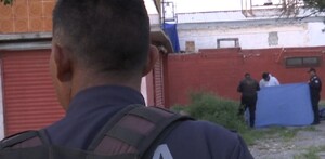 Se observa a un policía de espalda y unas personas al fondo sosteniendo una manta azul.