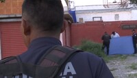 Se observa a un policía de espalda y unas personas al fondo sosteniendo una manta azul.