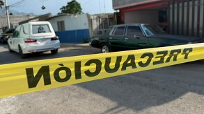 Se ven de fndo unos carros estacionados y una cinta amarilla de precaución.