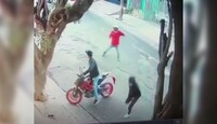 Captura de pantalla de un video de seguridad que muestra a dos presuntos asaltantes tratando de robar la moto de un hombre en medio de la calle