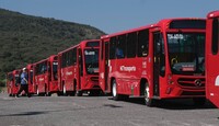 Camiones rojos del transporte público en Guadalajara de las rutas troncales estacionados en fila en un terreno despejado con un cerro de fondo
