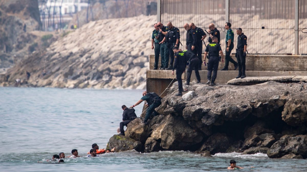 Migrantes cruzan a nado por la playa del Tarajal hacia Ceuta, donde el colapso obliga a cientos de personas a dormir en plena calle. (Archivo AP)