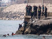 Migrantes cruzan a nado por la playa del Tarajal hacia Ceuta, donde el colapso obliga a cientos de personas a dormir en plena calle. (Archivo AP)