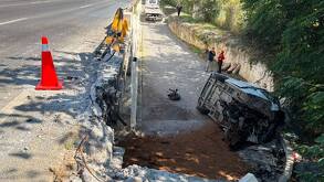 Cuerpos de emergencia laboran en la zona donde la unidad volcada quedó sobre uno de sus costados tras precipitarse desde la vía.