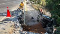 Cuerpos de emergencia laboran en la zona donde la unidad volcada quedó sobre uno de sus costados tras precipitarse desde la vía.