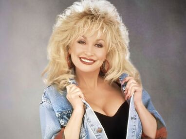 Dolly Parton posando con una de sus características sonrisas y vistiendo uno de sus célebres vestuarios | Pinterest