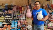 El maestro don Darío Medina, representante de la tercera generación de Alfarería El Medina, sostiene unas jarras de barro pintadas a mano