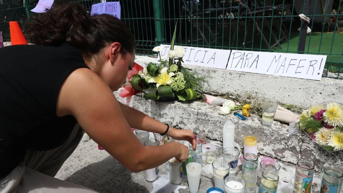 Una joven coloca una veladora en un altar en homenaje a María Fernanda Orozco Suárez en inmediaciones de la UDLAP | Melanie Torres