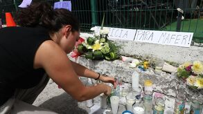 Una joven coloca una veladora en un altar en homenaje a María Fernanda Orozco Suárez en inmediaciones de la UDLAP | Melanie Torres