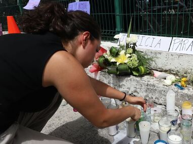 Una joven coloca una veladora en un altar en homenaje a María Fernanda Orozco Suárez en inmediaciones de la UDLAP | Melanie Torres