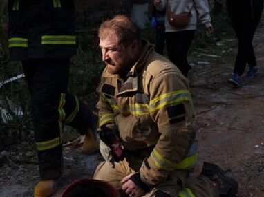 Un rescatista se sienta en el piso junto a un edificio residencial destruido en un ataque con misiles rusos, en Pryluky, Ucrania/ AP